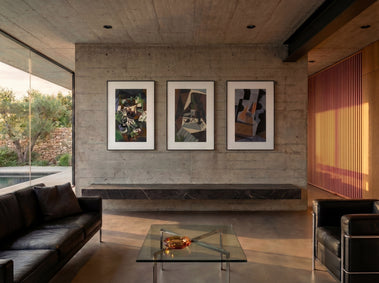 Three framed Inkposter art prints displayed on a concrete wall in a modern living room