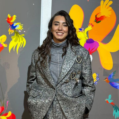 Art curator Anna Avetova standing in front of a colorful artwork with tropical birds