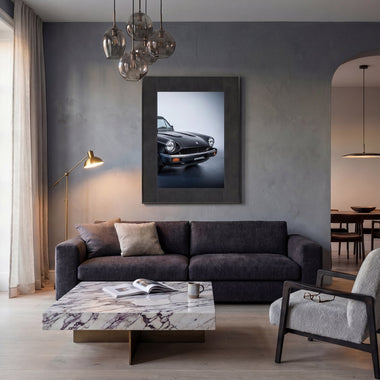 InkPoster Duna by Pininfarina above a sofa in a modern living room, displaying a photograph of a classic black sports car