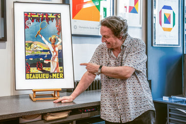 Jean-Daniel Clerc speaking beside an InkPoster color ePaper art display during a gallery interview